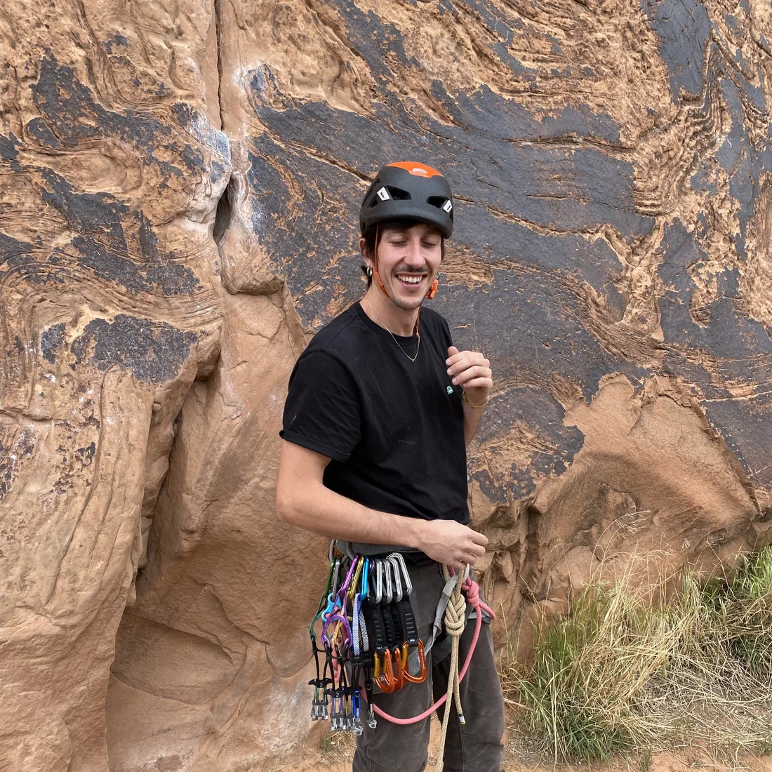 Julian climbing gear on, at the foot of a sandstone wall